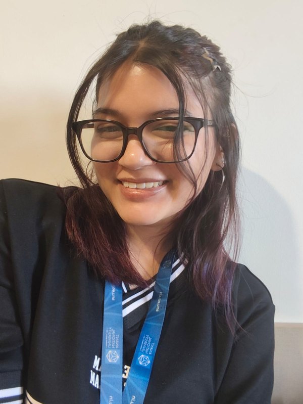 Siddhi smiling, wearing glasses and a lanyard